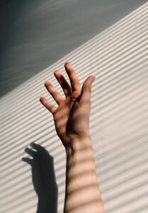 persons-left-hand-on-white-window-blinds
