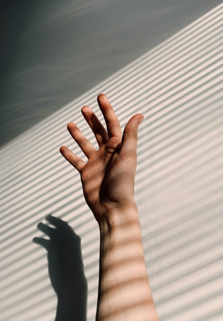 persons-left-hand-on-white-window-blinds